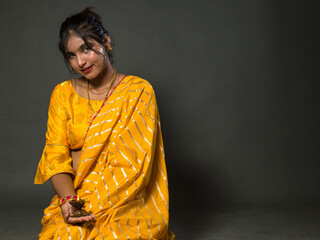 Beautiful Girl in Indian saree holding diwali diya(oil lamp) on gray background. Happy Diwali. Diwali is biggest festival of India. Diwali is festival of lights and happiness.