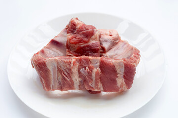 Raw pork ribs in white plate on white background.