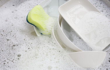 Washing dishes, Close up of utensils soaking in kitchen sink.