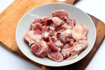 Raw pork ribs in white plate on cutting board on white background.