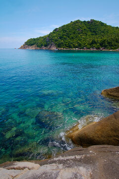 Kristallklares blaues gr&uuml;nes Wasser an Felsenk&uuml;ste bei Korallenriff in Thailand Mango Bay Hochformat