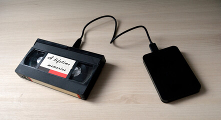 A video tape labeled  as 'A lifetime memories' plugged to a hard disk drive as a symbol of data...