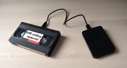 A video tape labeled  as '20th century memories' plugged to a hard disk drive as a symbol of data...