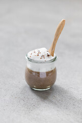 Vegan dish, mushroom cappuccino, champignon soup puree with milk foam in a glass jar on a light gray background