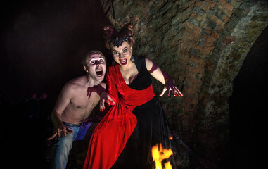 Halloween. Images of the dead vampires and witches. Man and woman vampires conjure near the fire.