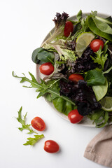 Healthy vegetable salad of fresh cherry tomato and green leaves mix on plate. Top view. White background. 