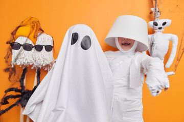 Indoor shot of small kid poses near mummy has fun before Halloween party goes trick or treating...