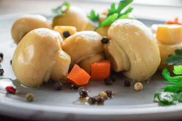 marinated champignons in a close-up gray plate with herbs, carrots, peppercorns