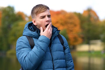 Portrait of tired exhausted sleepy handsome man, young yawing guy is yawn with his mouth open...