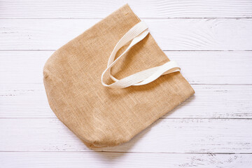 Top view of reusable Sackcloth bag with white holder on white wooden background , go green and eco concept