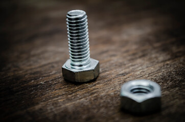 Metal bolt and nut on old wooden background stylized blur background