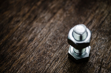 Metal bolt and nut on old wooden background stylized blur background