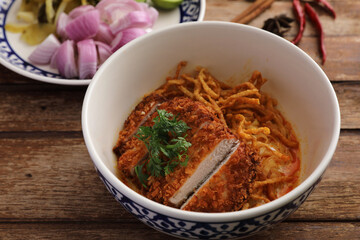 Local northern Thai food Egg noodle curry with fried pork on wood background