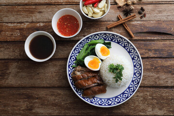 Local Thai food stewed pork leg on rice isolated in wood background