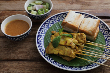 Local Thai food pork satay with oeanut dipping sauce isolated in wood background