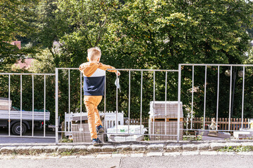 Kind schaut auf Baustelle, hat Coronamaske am Handgelenk