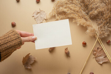 girl's hand and card in it. greeting mockup autumn mood, fall season. dry leaves, cozy atmosphere