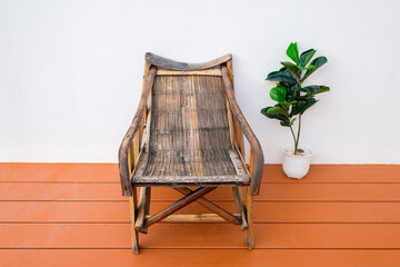 Old bamboo armchair at the wood terrace outside the new house, contrast of traditional old...