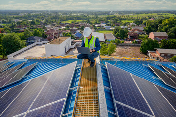 An engineer uses a laptop computer to monitor the photovoltaic system on the roof of a house...