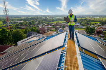 An engineer uses a laptop computer to monitor the photovoltaic system on the roof of a house...