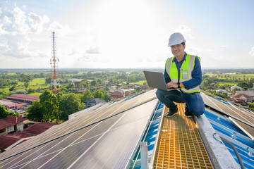 An engineer uses a laptop computer to monitor the photovoltaic system on the roof of a house equipped with solar panels using solar energy.