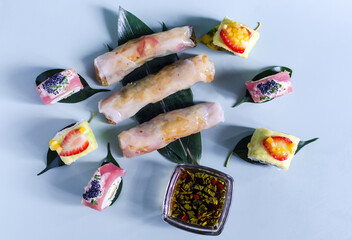 Spring rolls of seafood and vegetables with a decor of green leaves on a light background. Spring rolls close-up asian cuisine	
