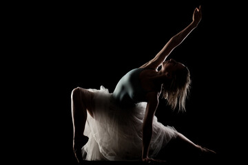 ballerina with a white dress and black top posing on black background. side lit silhouette. © Nikola Spasenoski