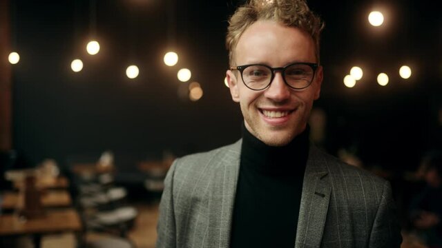 Close-up portrait of nice-looking handsome young businessman looking into camera. Attractive office worker in cafe. Successful people. High quality 4k footage