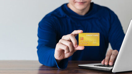Businessman hand holding credit card with using laptop for online shopping while making orders at home. business, lifestyle, technology, ecommerce, digital banking and online payment concept.