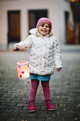 Little kid girl holding selfmade lanterns with candle for St. Martin procession. Healthy cute...