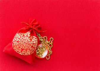 Money in Red bag and gold necklace on red texture background. Greeting cards for good luck and happiness in the Chinese New Year.