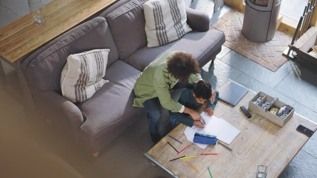 Slow motion of man helping son draw, overhead