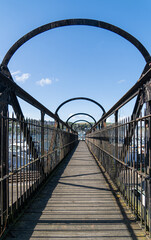 wooden railway bridge accross steam railway tracks with marina in background devon UK trailing perspective image