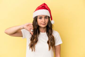 Young caucasian woman celebrating Christmas isolated on yellow background showing a dislike gesture, thumbs down. Disagreement concept.