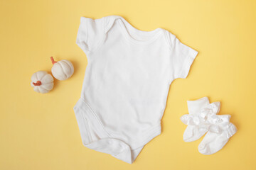 Baby clobodysuit mock-up with pumpkins on yellow background for your text or logo place in autumn season