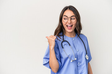 Young caucasian nurse woman isolated on white background points with thumb finger away, laughing and carefree.