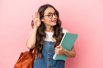 Young caucasian student woman isolated on pink background trying to listening a gossip.