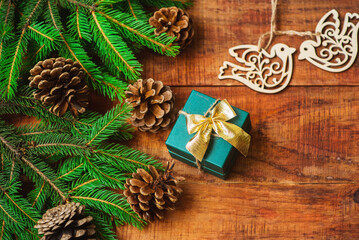 Christmas background. Spruce branches, wooden bird figures and gift on a wooden background.