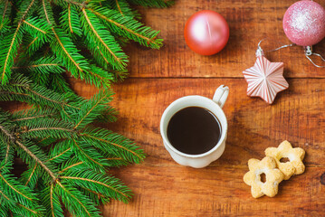 Obraz na płótnie Canvas Christmas background. Composition of spruce branches, Christmas balls, cup with coffee with cookies on a wooden background. Copy space Top view. Christmas or New Year's card. flat lay