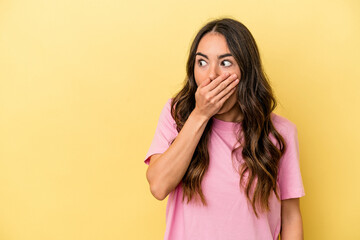 Young caucasian woman isolated on yellow background thoughtful looking to a copy space covering mouth with hand.