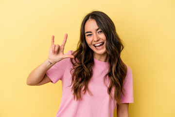 Young caucasian woman isolated on yellow background showing a horns gesture as a revolution concept.
