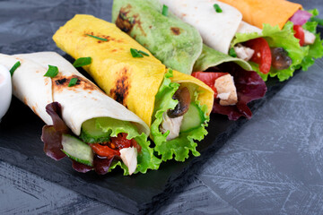 Assorted wraps with tortillas of various colors with chicken, vegetables, mushrooms, herbs and...