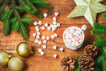Christmas background. Spruce branches Christmas balls, cup with coffee with marshmallows and golden star on a wooden background. Copy space Top view. Christmas or New Year's card. flat lay