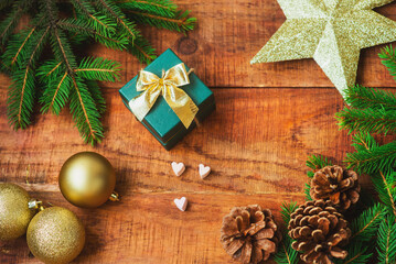 Christmas background. Spruce branches, Christmas balls, cones, golden star and gift on a wooden background. Copy space Top view. Christmas or New Year's card. flat lay