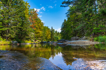 Fototapeta na wymiar The clear waters of the Ammonoosuk River amid woods and smooth granite slabs off Mount Washington in the White Mountain National Forest in New Hampshire.