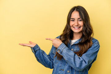 Young caucasian woman isolated on yellow background excited holding a copy space on palm.