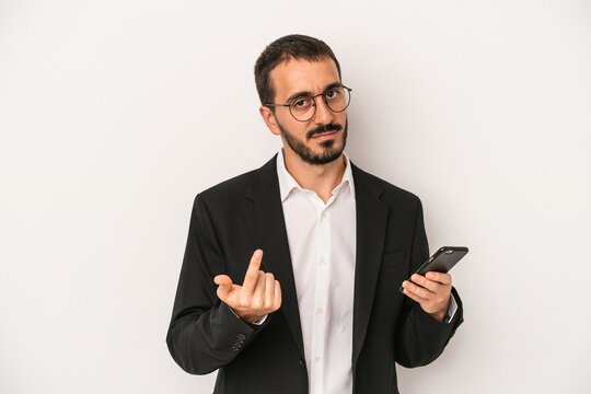 Young business man holding a mobile phone isolated on white background pointing with finger at you as if inviting come closer.