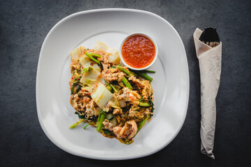 Selective focus on stir fried thai sukiyaki with pork spicy sauce in the white dish on the gray concrete table.