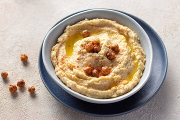 chickpea hummus in a ceramic bowl on beige background. Mediterranean popular snack of chickpeas and tahini. close-up