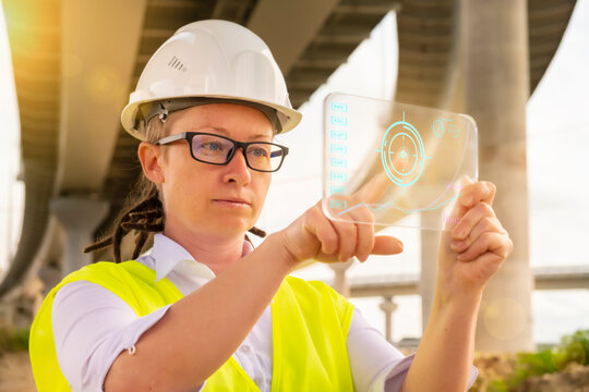Woman engineer or inspector using futuristic tablet works on construction of road bridge.